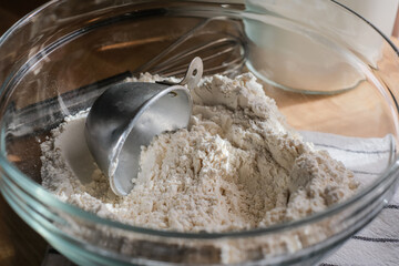 Close up the heap of flour with measuring cup in the glass bowl for food and baking concept.