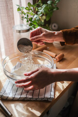 A woman is measuring the flour for baking dessert and food in the warm and decorative kitchen.
