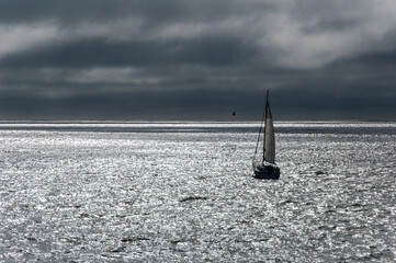 A sailboat sailing in the Atlantic Ocean under a stormy sky