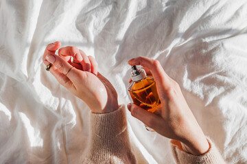 Woman applying perfume on her hand in morning light, lifestyle
