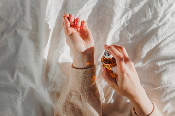 Female hands holding a bottle of perfume in natural morning light
