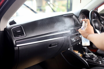 male hand using polishing spray to clean car dashboard. car interior leather care.