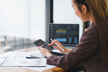 Businesswoman or an accountant team are analyzing data charts, graphs, and a dashboard on a laptop screen in order to prepare a statistical report and discuss financial data in an office. - obrazy, fototapety, plakaty