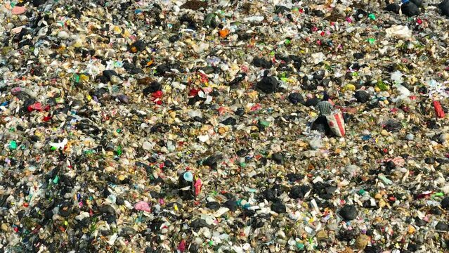 A landfill reveals a dense amalgam of debris, showcasing diverse colors and shapes of waste, spotlighting the environmental impact of consumerism. Landfill background. 4K aerial view.
