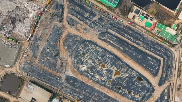 Seen from the sky, a landfill is shrouded in black plastic, a fruitless endeavor to hide the consequences of our consumption. Landfill background. 4K aerial view.
