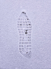 Footprint of the sole of a right shoe isolated on white snow with copy space.