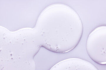 Oil drops. Liquid gel texture with bubbles. Cosmetic product on light purple color background