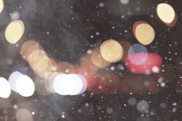De focused/blur image of city at winter night. Snowflakes with blurred urban abstract traffic...