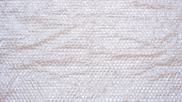White plastic bubble wrap texture on cardboard paper sheet background, top view with copy space