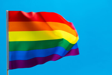 Rainbow flag waving on blue background
