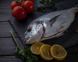 Sea bream or dorado sea fish herbs on dark slate background Top view 