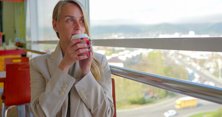 Young woman drinking fragrant coffee, espresso at a fast food restaurant