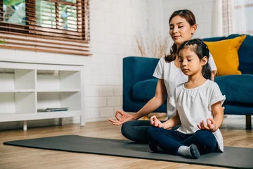 Tuinposter A mother teaches her daughter family yoga focusing on mindfulness and meditation in lotus position. Their smiles showcase happiness togetherness and growth. © sorapop