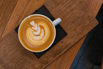 Nice Texture of Latte art on hot latte coffee . Milk foam in heart shape leaf tree on top of latte art from professional barista artist.
