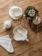 Aesthetic breakfast setting - ceramic tableware, tea pair, bowl, teapot, decor on a wooden table, top view