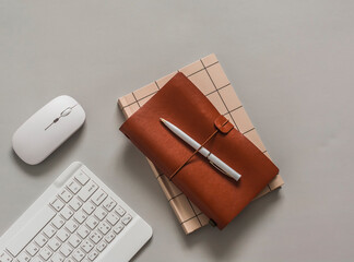Business, finance, education concept. Keyboard, computer mouse, notebook in a leather cover on a gray background, top view