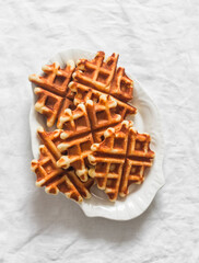 Orange peel and dried apricots waffles on a light background, top view
