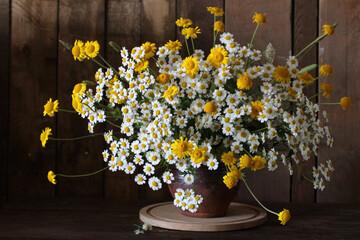 rustic still life with a bouquet of daisies on a dark wooden background. summer.