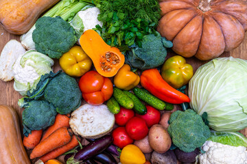 Various vegetables are laid out on a wooden table. Large assortment of vegetables food. pumpkin cabbage broccoli pepper tomatoes carrots and others - obrazy, fototapety, plakaty