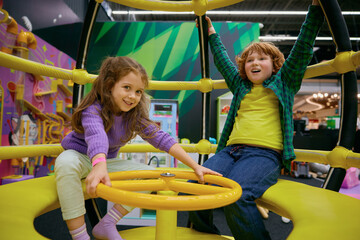 Fototapeta na wymiar Happy excited children playing on indoor carousel at play center
