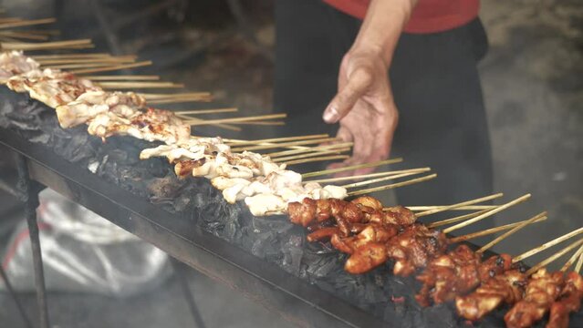 Preparing satay sate taichan for customers. Sate skewered and grilled meat served with spicy salad, chili, cucumber and soy sauce. In Java, as a local take on the skewered kebab introduced.