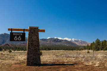 route 66 sign with snow capped mountains in background