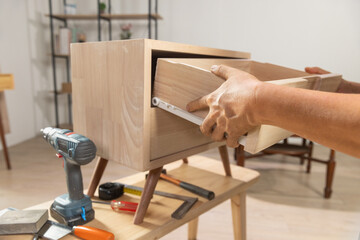 Handyman fixing over tight drawer slides rail of bedside table. - 784273258