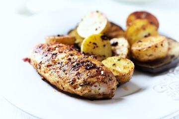 Grilled Chicken Breast with oven baked potatoes. Bright background. Close up.