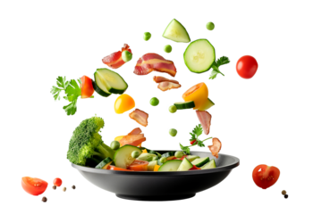 Vegetables fall into a black frying pan on a transparent background. Healthy food concept