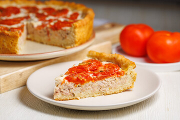 Piece of homemade tuna quiche with tomatoes on plate