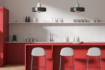 A modern kitchen interior with red cabinets, concrete countertop, and stylish pendant lamps on a...