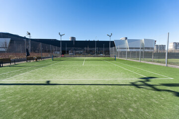 Landscaped areas of a residential development with a tennis court with high Plexiglas and metal...