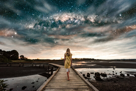 Girl walking on boardwalk under the Milky Way stars