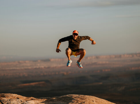 Man leaps and jumps as high as he can in barren desert