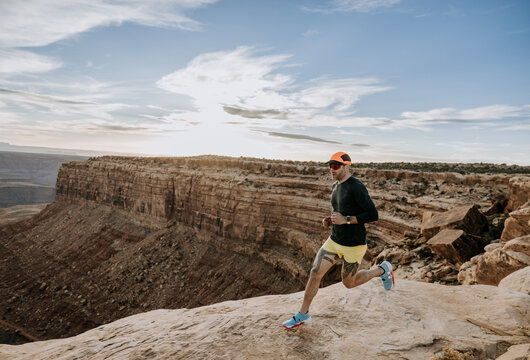 Male trail runner with tattoos jogs through desert landscape