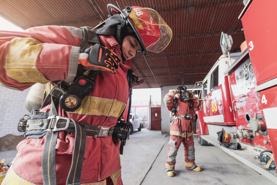 Female firefighter with workwear working at fire engine