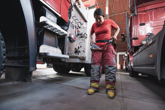 Female firefighter wearing fire protection suit against fire engine