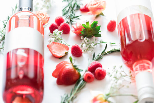 Two rose bottle laying on white backdrop with strawberries and r