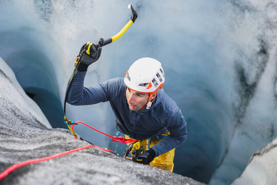 Young man ice climbing up a crevasse on an Icelandic glacier