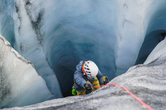 Man ice climbs inside a dark deep crevasse on an Icelandic glacier