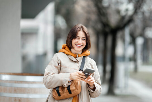 Young Stylish Woman with Smartphone Smiling on City Street