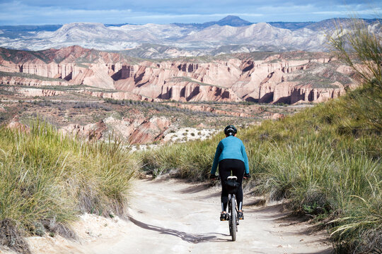 Cyclist woman riding into desert canyon.