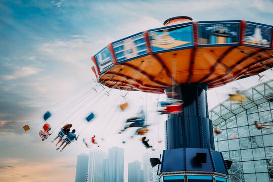 Colorful carnival swing ride with cityscape in background