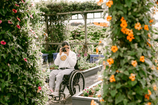 Teen female on wheelchair taking photos in garden