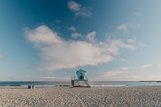 State beach lifeguard tower at empty beach with surfers in water