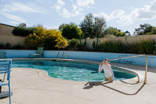 young girl climbing out of swimming pool on sunny day