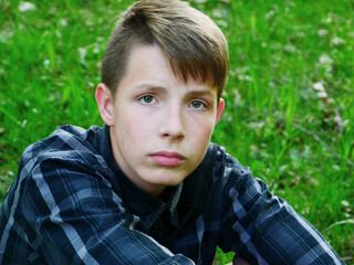 Close-up portrait of a boy against a background of green grass.