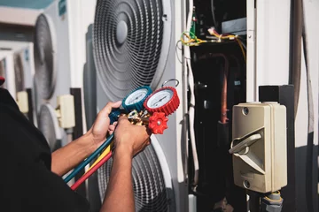 Poster Heat and Air Conditioning, HVAC system service technician using measuring manifold gauge checking refrigerant and filling industrial air conditioner after duct cleaning maintenance outdoor compressor. © Eakrin