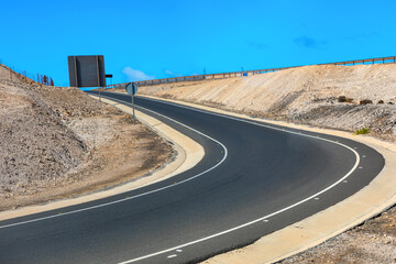 Curve of the road on the mountain with blue sky background. Asphalt Road in the Desert on a Sunny Day