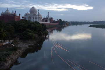 
"Mesmerizing sight of Taj Mahal mirrored in the tranquil river, its grandeur reflected in the serene waters."